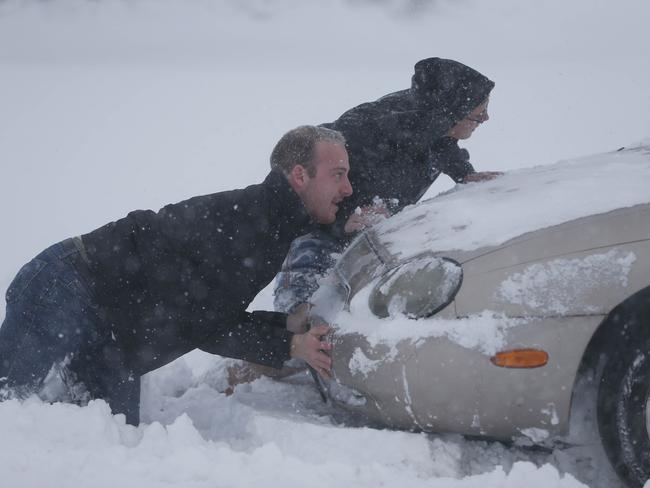 Stuck ... Eric Dehond, left, and Dakota Paciorkowski help push out a stuck motorist on George Urban Boulevard in Depew, New York on Tuesday. Pic: AP Photo/The Buffalo News, Derek Gee