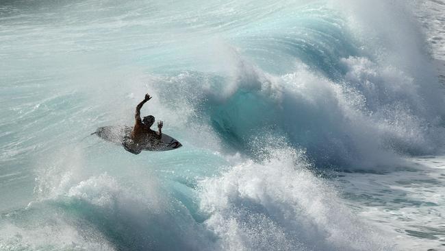 A surfer is seen at Duranbah, the northernmost beach in New South Wales, Thursday February 21, 2019. Huge swells and high tides are set to pummelling south-east Queensland and far-northern New South Wales beaches over the coming days as Cyclone Oma tracks towards the Queensland coast. (AAP Image/Dave Hunt)