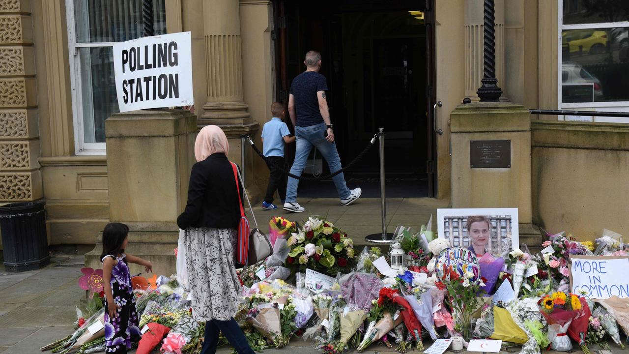 TOPSHOT - People pass floral tributes to murdered MP Jo Cox outside Batley Town Hall as they arrive to vote in the EU referendum in Batley, northern England on June 23, 2016.    Millions of Britons began voting today in a bitterly-fought, knife-edge referendum that could tear up the island nation's EU membership and spark the greatest emergency of the bloc's 60-year history. / AFP PHOTO / OLI SCARFF