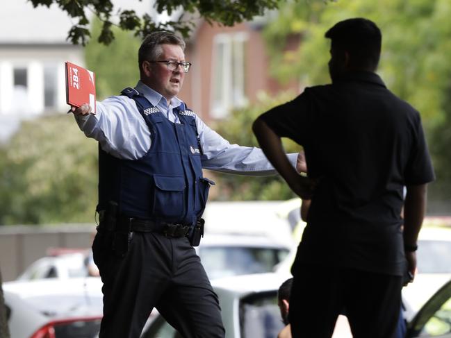 A police officer attempts to move people away from across the road from a mosque in central Christchurch, New Zealand. Picture: AP