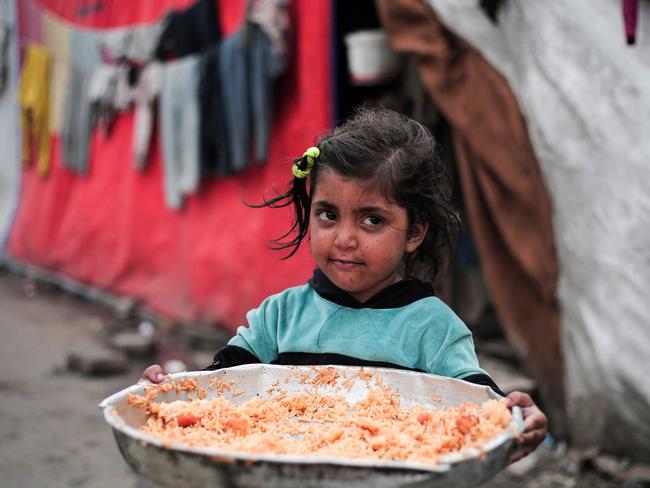A Palestinian girl holds a plate of rice outside her tent at a refugee camp in Rafah in the southern Gaza. Picture: AFP