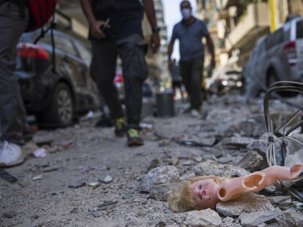 People walk past a child's doll that was blown out of a nearby building during the massive explosion. Picture: Daniel Carde/Getty Images