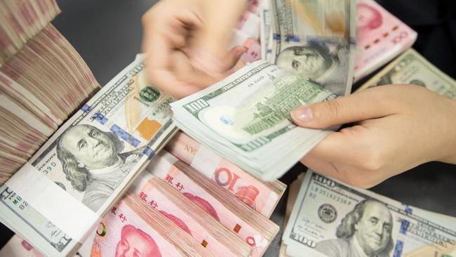 A Chinese bank employee counts 100-yuan notes and US dollar bills at a bank. Picture: STR / AFP.