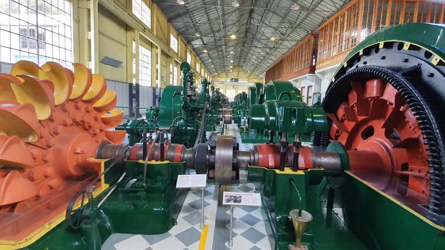 The turbine hall at the Waddamana power station  museum complete with its antique Pelton wheels, buckets and turbine cases which are freshly painted in shades of red, yellow and orange and lustrous and dark British racing green.