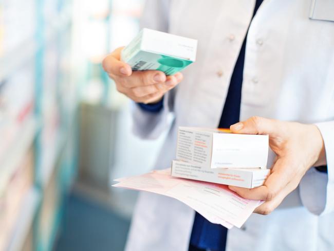 Closeup of pharmacist's hands taking medicines from shelf at the pharmacy