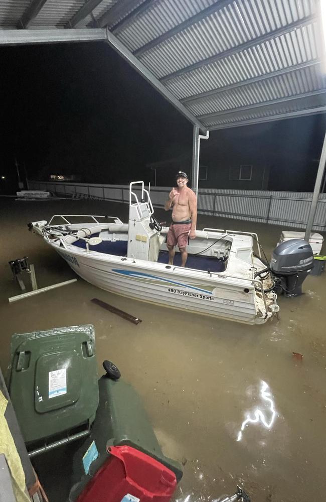 Cardwell resident Brent Churton launches a dinghy from his car port before whisking nearby residents to safety before their home flooded.