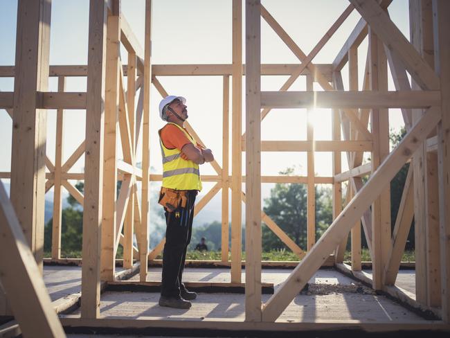 Shot of a senior builder working on wooden house in nature.