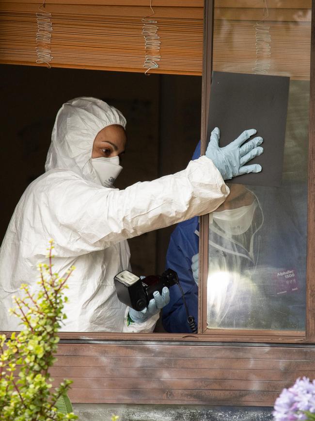 Forensic police comb the house where her body was found.