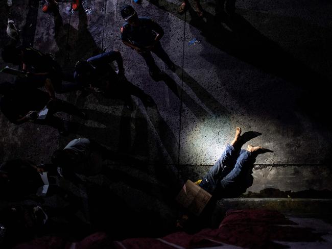 Police officers investigate a dead body of an alleged drug dealer as Duterte ends his first year as Philippine president taking Filipinos on a promised ‘rough ride’ of drug war killings and foreign policy U-turns. Picture: Noel Celis/AFP