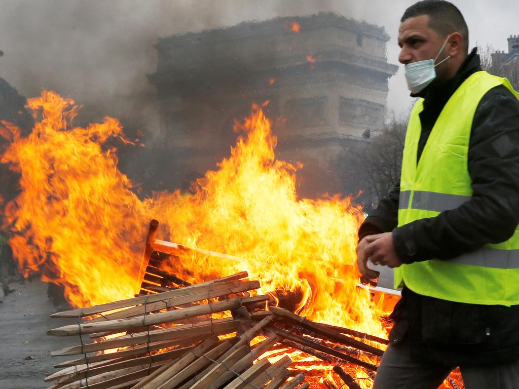 A demonstrator walks past a fire during a protest of Yellow vests (Gilets jaunes) against rising oil prices and living costs, near the Arc de Triomphe, in Paris. Picture: AFP