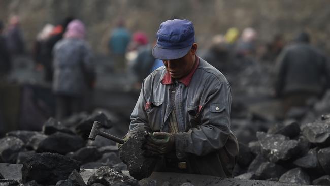 A worker sorting coal on a conveyor belt near a coal mine at Datong in northern China's Shanxi province. Picture: AFP