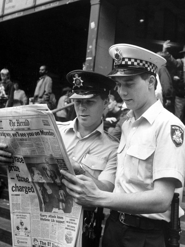 Two police officers reading the last edition of The Herald before it merged with the Sun, outside Flinders Street Station.