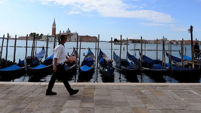 Gondoliers walks past a row of gondola boats as he wait for tourists in Venice. Picture: AFP