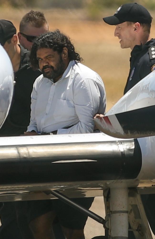 Terence Darrell Kelly boards a plane after being taken into custody by members of the Special Operations Group at Carnarvon airport. Picture: Getty