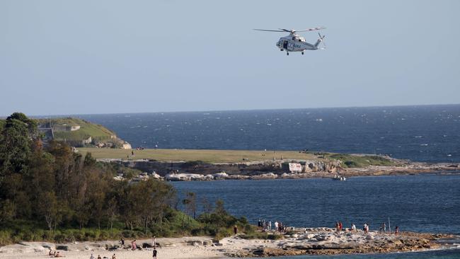 A helicopter and police searches the rocks and water at Yarra Bay. Picture: Damian Shaw