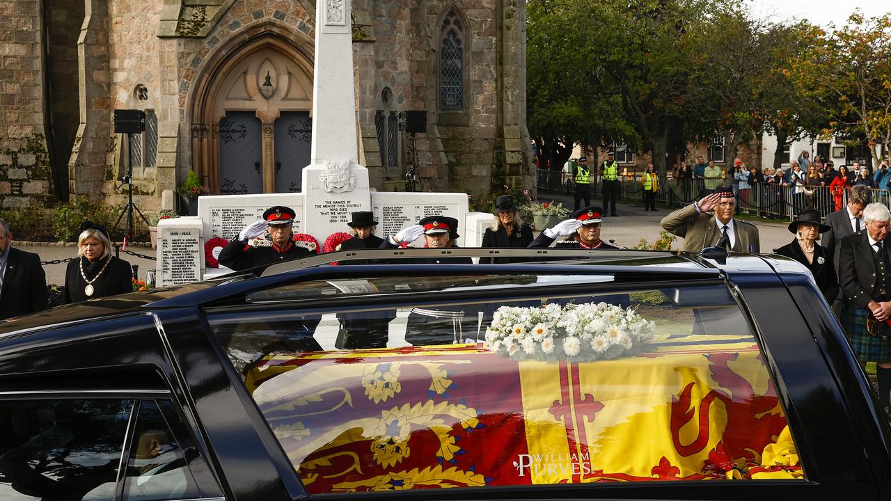 People salute as they stand in tribute as the cortege carrying the coffin of the late Queen Elizabeth II passes by on September 11, 2022 in Ballater. Picture: Jeff J Mitchell/Getty Images