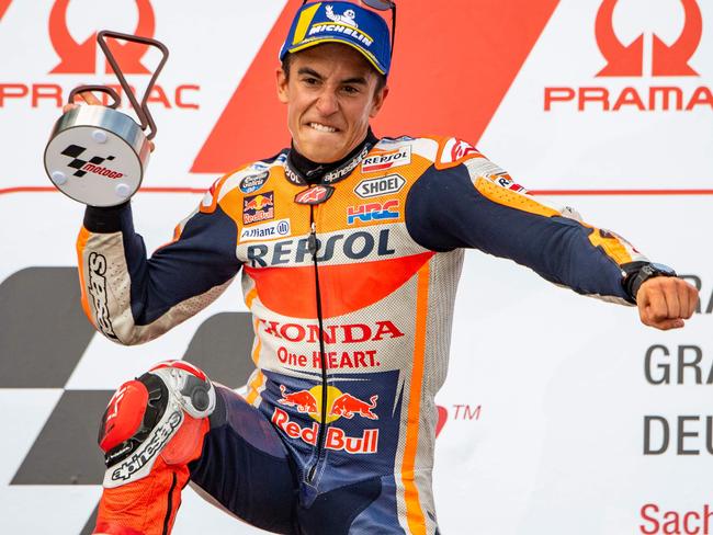 TOPSHOT - Spanish Honda rider Marc Marquez celebrates in front of second placed Italian Yamaha rider Valentino Rossi on the podium after winning the Moto GP race at the Grand Prix of Germany at the Sachsenring Circuit on July 15, 2018 in Hohenstein-Ernstthal, eastern Germany. / AFP PHOTO / Robert MICHAEL