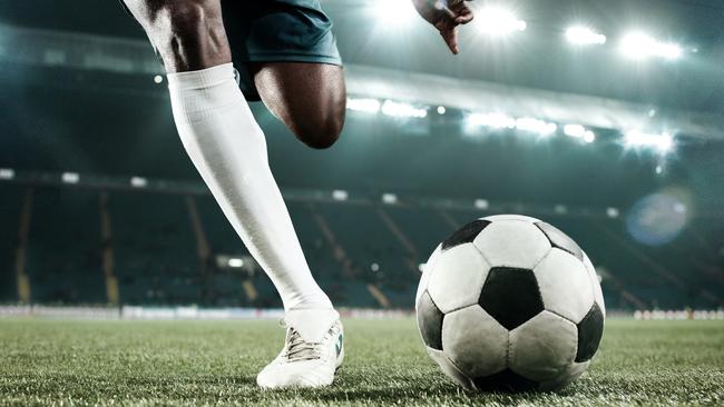 Legs of african soccer player kicking the ball at stadium istock image