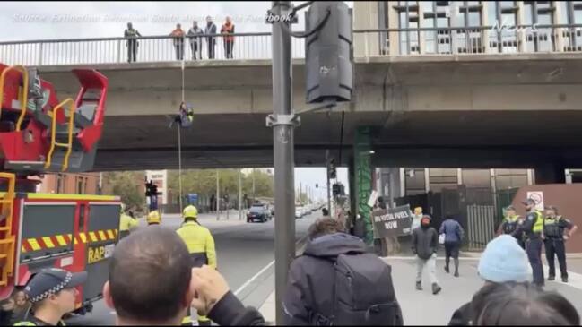 Extinction Rebellion protesters hang from Morphett St bridge in Adelaide