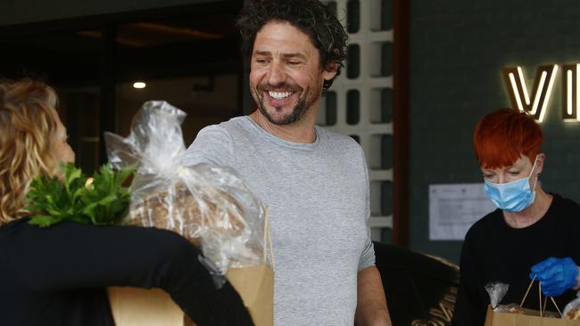 Colin Fassnidge sends a member of the community away with bread and a bag of food items at his soup kitchen in the carpark of the Banksia Hotel. Picture: John Appleyard