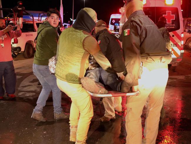 Police officers carry an injured migrant following a fire that killed dozens of migrants, in the immigration station in Ciudad Juarez, Chihuahua state on March 28, 2023, where at least 39 people were killed and dozens injured after a fire at the immigration station. (Photo by HERIKA MARTINEZ / AFP)