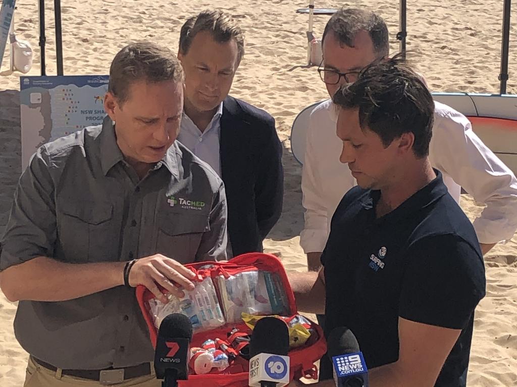 Mike Brewer (far left), from Tacmed Australia, the company supplying the shark attack trauma kit, shows the contents of the first aid kit it has developed to, from left to Manly MP, James Griffin, NSW Agriculture Minister Adam Marshall and Surfing NSW CEO Luke Madden, on Manly Beach. Picture: Jim O'Rourke