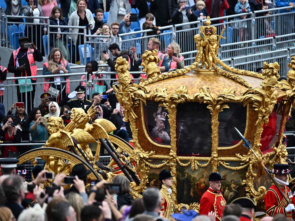 Attendees take pictures of the hologram of Queen Elizabeth II projected on the Gold State Coach during the Platinum Pageant in London. Picture: AFP