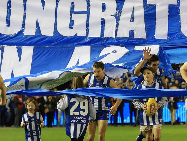 Brent Harvey runs through the banner with his children. Picture: Wayne Ludbey