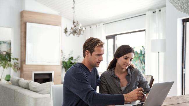 Shot of a couple using a laptop together while going through paperwork at home