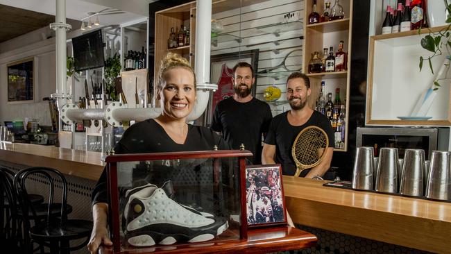 Harry's Steak Bistro and Bar has only been open for two years, but they have decided to give it a revamp, now including newly built sports bar. The owners are calling for locals to bring in their memorabilia (either from local comps, or big sporting stars) so they can show it off. Joanne Hartmann with her signed jersey and shoes signed by professional basketball player Michael Jordan with bar owners Adam Haralampou and Pete Tayler. Picture: Jerad Williams