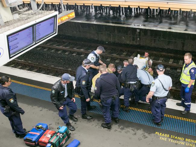 Emergency workers haul the man from the train tracks at Sydenham train station. Picture: Damian Hofman