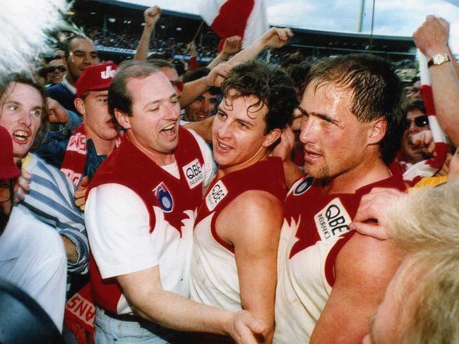 Tony Lockett and Leo Barry are swamped by jubilant Swans supporters after a win.