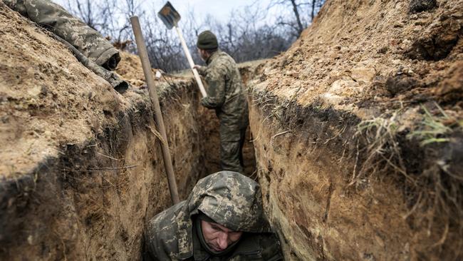 A Ukrainian infantryman takes cover in a partially dug trench along the frontline facing Russian troops 250m away on Sunday. Picture: Getty Images