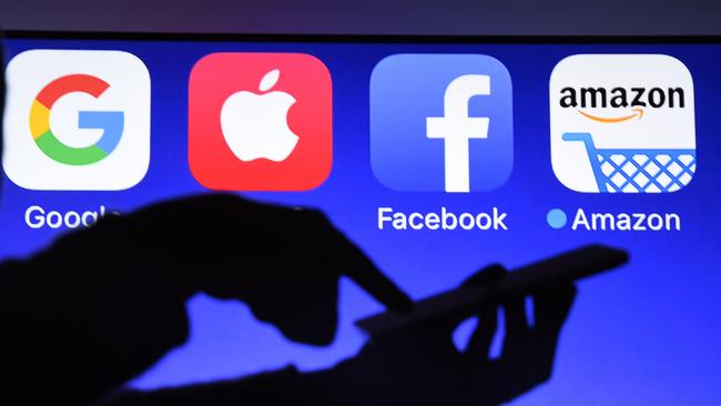 This photograph taken on September 28, 2017, shows a smartphone being operated in front of GAFA logos (acronym for Google, Apple, Facebook and Amazon web giants) as background in Hédé-Bazouges, western France. / AFP PHOTO / Damien MEYER