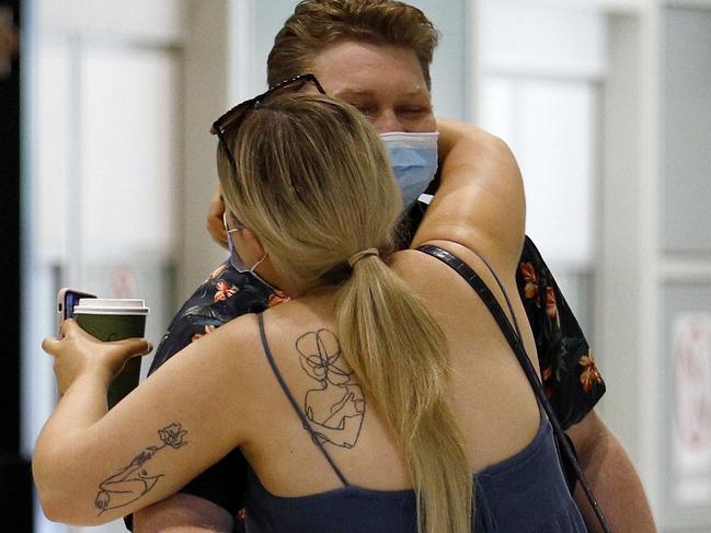 BRISBANE, AUSTRALIA - NewsWire Photos NOVEMBER 19, 2021: Passengers arriving from Sydney into Brisbane airport are seen being processed by border police before they are allowed to leave the airport to quarantine for 2 weeks. Pictured is a couple embracing after being apart. Picture: NCA NewsWire/Tertius Pickard