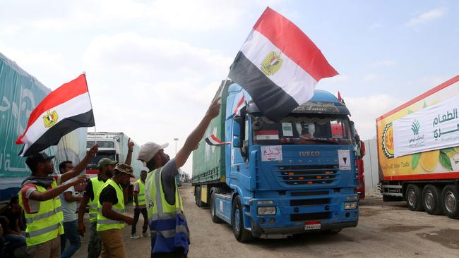 People on the Egyptian side of the Rafah border crossing wave flags as a convoy of lorries carrying humanitarian aid crosses to the Gaza Strip on October 22, 2023. Picture: AFP