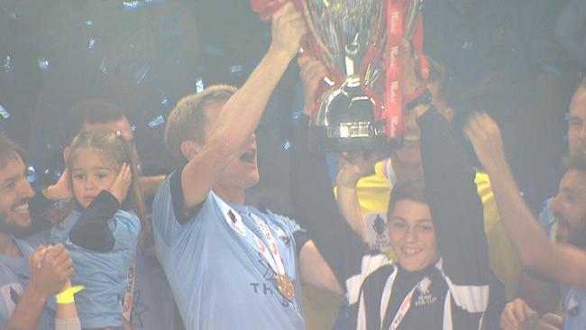 Matt Simon raises the FFA Cup trophy with the ball boy.