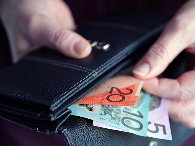 Adult woman female hand pulling out Australian money from a leather wallet.