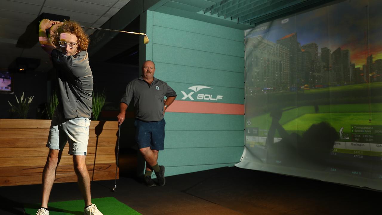 Joel Lucas (left) takes a swing using X-Golf technology, while Russell (right) has seen his short game improve at the South Geelong venue. Picture: Alison Wynd