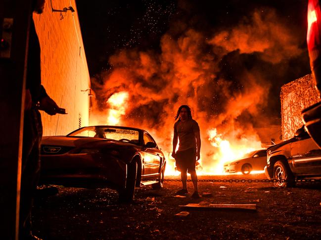 A man tries to toe away a car in a safe zone as the other car catches fire in a local parking garage in Minneapolis, Minnesota. Picture: AFP