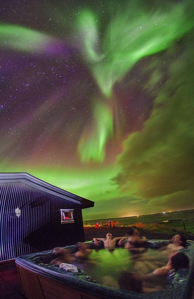 The northern lights form the shape of a bird above a jacuzzi filled with people at Hestheimar farm in southern Iceland. Picture: Juan Carlos Casado 