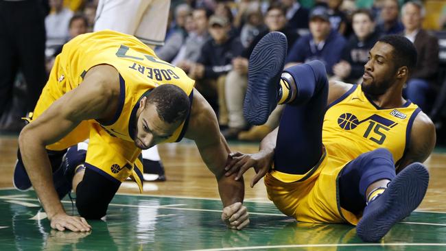 Utah Jazz's Rudy Gobert kneels on the floor beside teammate Derrick Favors.