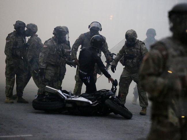 Authorities move through gas and detain a protester as demonstrators march in Atlanta.