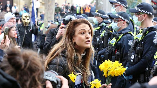 A woman carrying a bouquet of yellow daffodils approaches police officers. Picture: Matrix