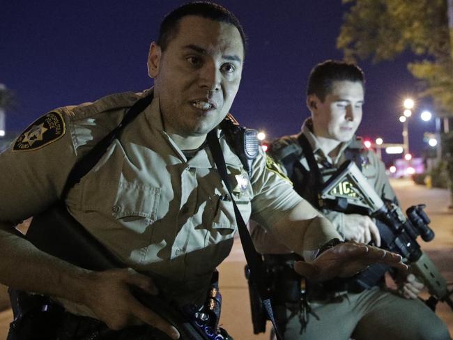 Police officers advise people to take cover near the scene of a shooting near the Mandalay Bay resort and casino on the Las Vegas Strip. Picture: AP