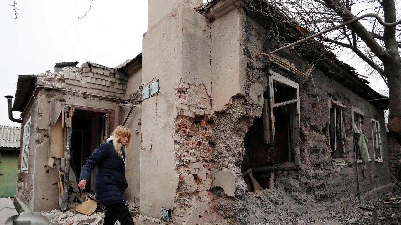 A local resident walks next to her damaged house in Donetsk, Ukraine. Picture: Alexander Ermochenko/Reuters