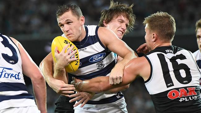 Joel Selwood tries to bust through an Ollie Wines tackle.