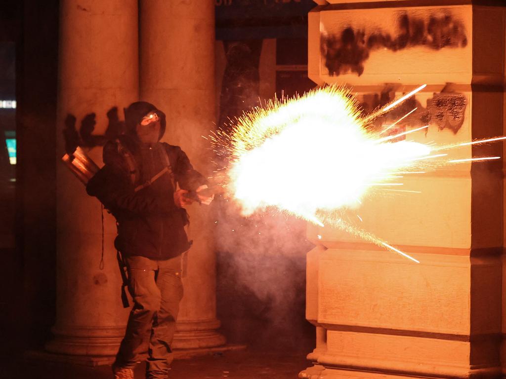 A protester shoots fireworks toward police during the fifth straight night of demonstrations against the government's postponement of EU accession talks until 2028, in central Tbilisi on December 2, 2024. (Photo by Giorgi ARJEVANIDZE / AFP)