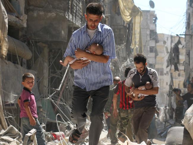 AFP PICTURES OF THE YEAR 2016 Syrian men carrying babies make their way through the rubble of destroyed buildings following a reported air strike on the rebel-held Salihin neighbourhood of the northern city of Aleppo, on September 11, 2016. Air strikes have killed dozens in rebel-held parts of Syria as the opposition considers whether to join a US-Russia truce deal due to take effect on September 12. / AFP PHOTO / AMEER ALHALBI