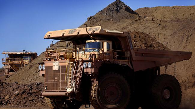 Heavy earth moving trucks at the Tom Price iron ore mine, operated by Rio Tinto Group, are lit up by the afternoon sun in Pilbara, north Western Australia on Wednesday, July 26, 2006. BHP Billiton Ltd., the world's largest mining company, is losing the support of investors and steelmakers for its proposed $128 billion takeover of Rio Tinto Group. Photographer: Jack Atley/Bloomberg News